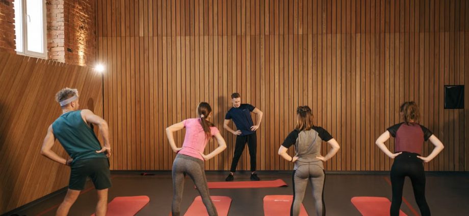 People stretching on yoga mats during a fitness class indoors.